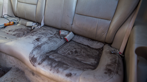 cream leather backseat of vehicle covered in ash and dirt