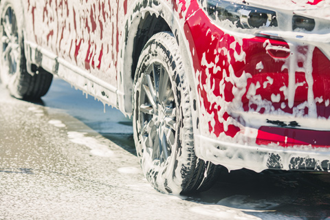 red car covered in soap suds from having valet done